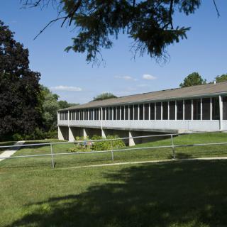 A modernist building surrounded by green lawns and trees under a clear blue sky.