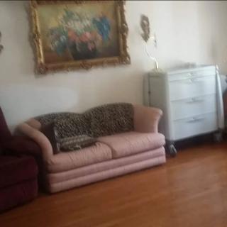 A cozy living room with a pink couch, decorative painting, and vintage dresser.