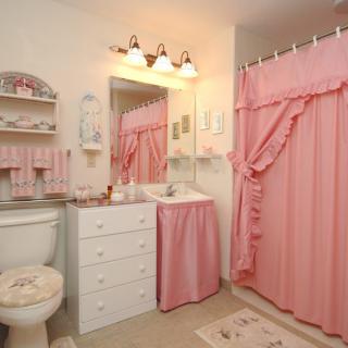 A cozy bathroom decorated with pink accents and a matching shower curtain, creating a warm and inviting atmosphere.