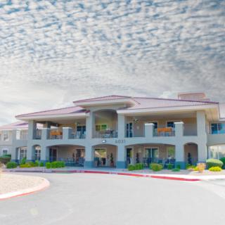 A two-story building with a cloudy sky backdrop and landscaped surroundings.