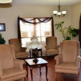 A cozy living room with four armchairs, a central coffee table, and natural lighting from a large window.
