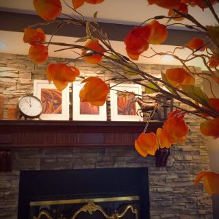A cozy fireplace mantel decorated with autumn leaves and a clock.
