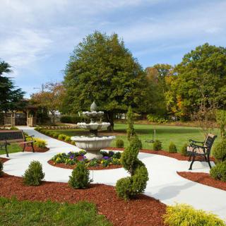 A beautiful garden with a fountain, surrounded by neatly arranged pathways and lush greenery.