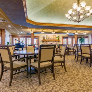 An elegant dining room with multiple tables and chairs, adorned with a chandelier.