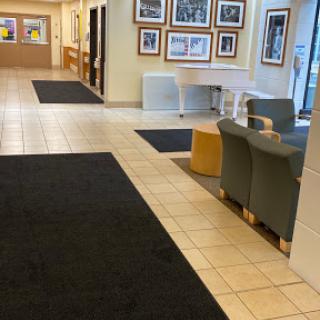 A spacious lobby showcasing framed photographs, comfortable seating, and a blend of tile and carpet flooring.
