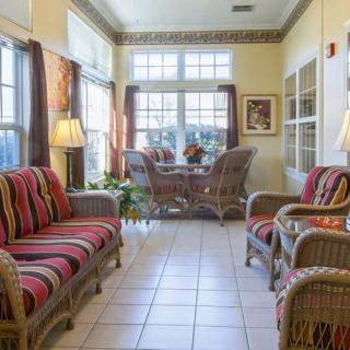 A cozy living room with wicker furniture and ample natural light streaming through large windows.