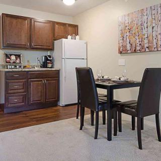 Compact kitchen and dining area with wooden cabinets and a small dining table.