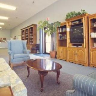 A cozy living room with armchairs, a coffee table, and wooden bookshelves.