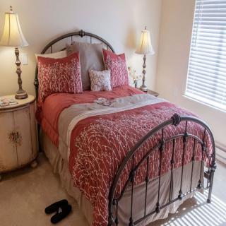 A cozy bedroom with a metal frame bed, floral bedding, and two lamps on side tables.