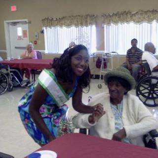 A young woman and an elderly person smiling together in a community setting.
