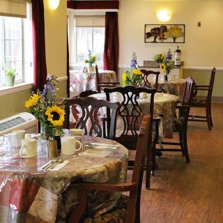 A cozy dining room with tables and chairs, decorated with fresh flowers.