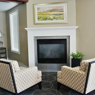 A modern living room with a fireplace and two patterned chairs.