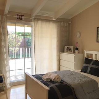 A cozy, well-lit bedroom with minimalist decor and neutral tones.