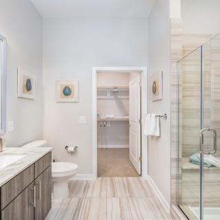 A modern and bright bathroom with a glass shower, vanity, and toilet.