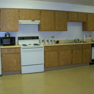 A kitchen with wooden cabinets and various appliances, including a stove and microwave.
