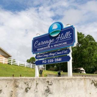 An outdoor sign for Carriage Hills Rehabilitation & Healthcare, featuring contact information and set against a grassy landscape.