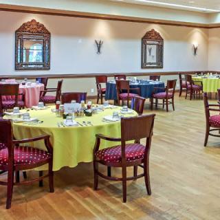 A spacious restaurant with neatly arranged dining tables and chairs, featuring elegant decor.