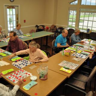 A group of seniors engaged in a game of bingo in a community room.