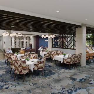 A modern restaurant dining area with neatly arranged tables and chairs, featuring stylish lighting and a patterned carpet.