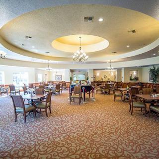 A spacious and elegantly designed dining area with multiple tables and chairs, featuring a decorative chandelier.