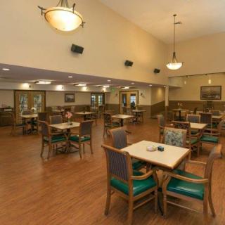A spacious dining area with neatly arranged tables and chairs, featuring warm lighting and a comfortable ambiance.