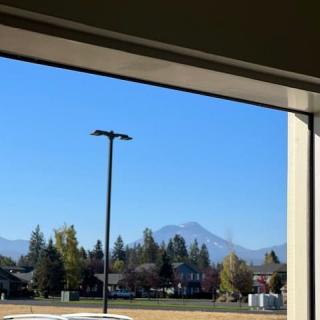 View of a mountain landscape through a window, with houses and trees in the foreground.