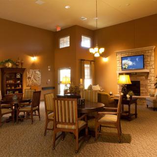 A cozy living room with warm lighting, featuring wooden furniture and a television near the fireplace.