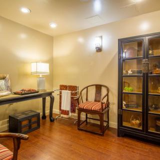 Cozy room interior with warm lighting, featuring chairs and a display cabinet.