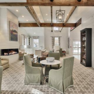 A spacious and modern living room featuring a beamed ceiling, fireplace, and neutral-colored furniture arranged in an open layout.