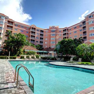 A scenic view of a residential apartment complex with a clear blue swimming pool under a bright sky.