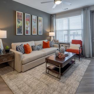 A modern living room with a cozy arrangement featuring a beige couch, colorful pillows, and wall art.