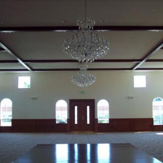 An empty hall with chandeliers and arched windows.