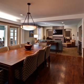 A cozy open-concept living and dining area with warm wood furnishings and elegant lighting.