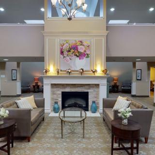 A modern lobby with a central fireplace, surrounded by sofas and elegant decor.