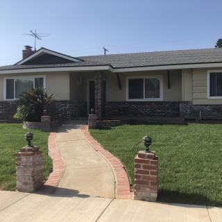 A single-story house with a well-kept lawn and a brick pathway leading to the entrance.