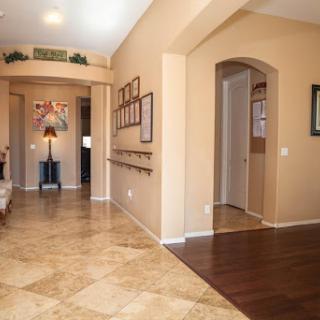 A bright and inviting hallway featuring a blend of tile and hardwood floors, with decorative elements and framed pictures adorning the walls.