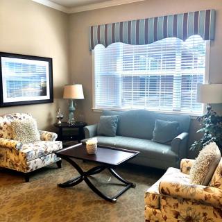 A cozy living room with a sofa, armchairs, and a coffee table near a large window.