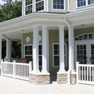 A modern house with a porch featuring white columns and railings.