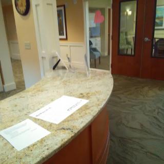 A reception desk with papers on a granite countertop in an office interior.
