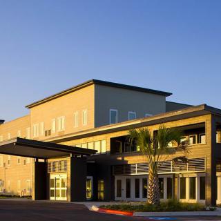 A modern commercial building with a prominent entrance under clear skies.