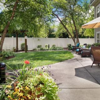 A charming backyard with a patio, garden, and outdoor seating under a sunny sky.