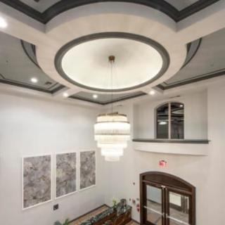 A modern lobby with a large chandelier and elegant ceiling design.