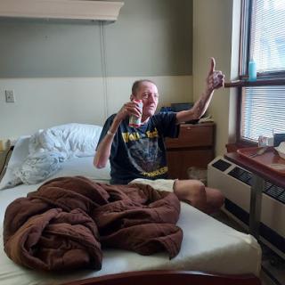 A patient sitting on a hospital bed, cheerfully posing by the window.
