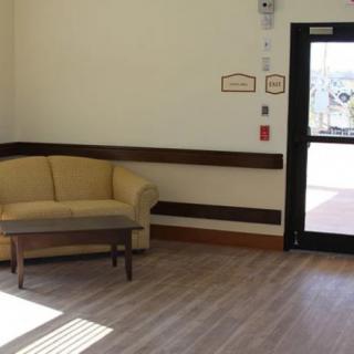 A quiet lobby with a sofa and small table next to a glass door.
