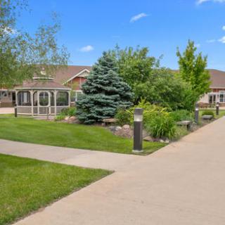 A serene residential garden showcasing lush greenery and a well-paved pathway under a clear blue sky.