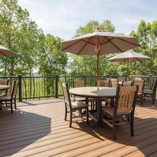 A serene outdoor deck with tables and umbrellas, surrounded by lush greenery.