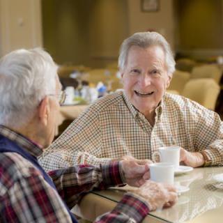 Two elderly men enjoying a conversation over coffee.