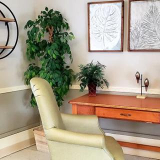 A cozy office corner featuring a desk, chair, indoor plants, and framed wall art.
