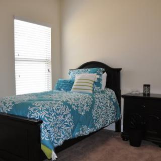 A cozy bedroom with a single bed and colorful bedding next to a nightstand.