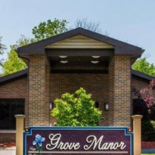 The front entrance of Grove Manor showcasing its sign and surrounding greenery.